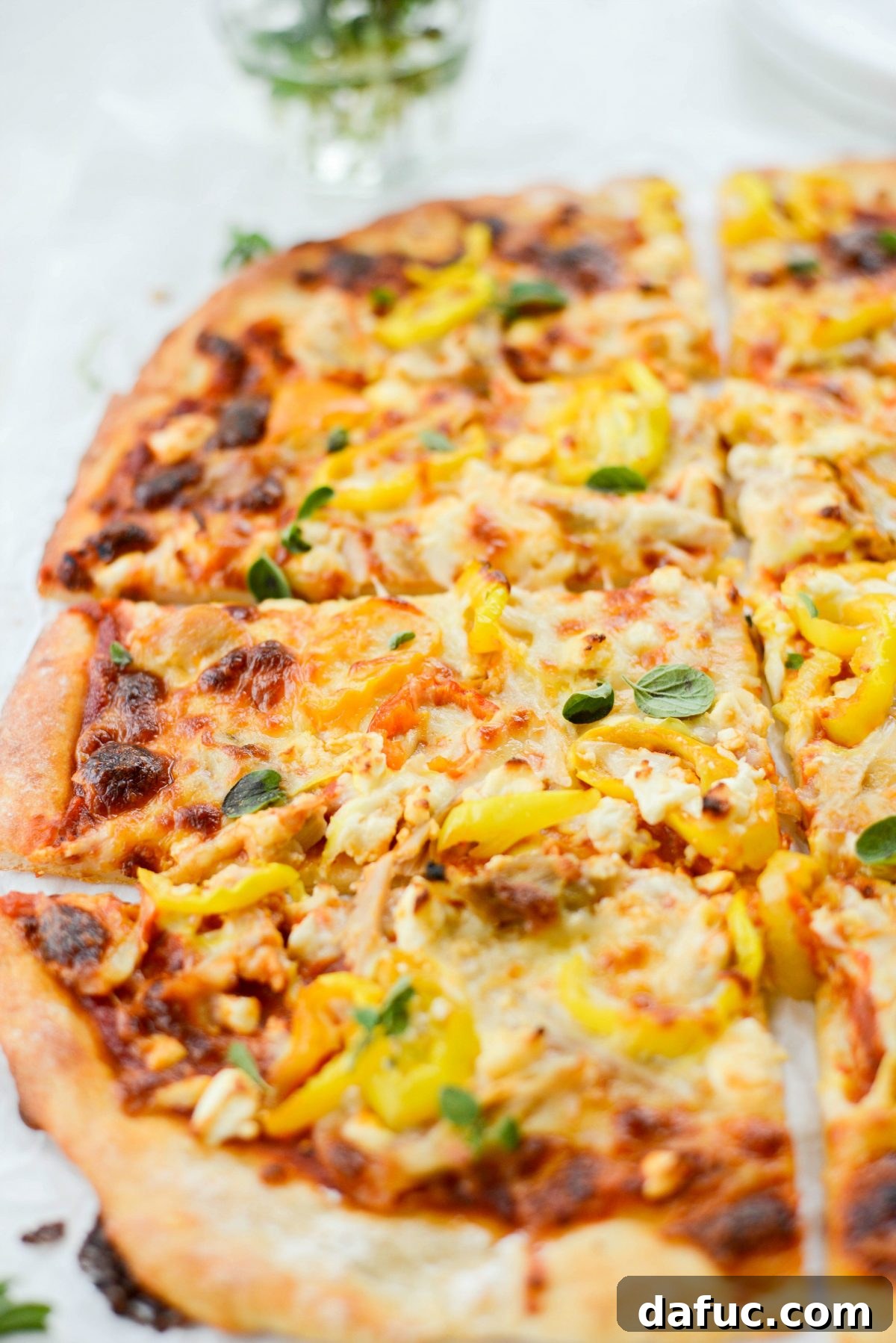 Closeup of a freshly baked Spicy Chicken Feta Pizza slice, showcasing melted mozzarella, feta, chicken, and banana peppers