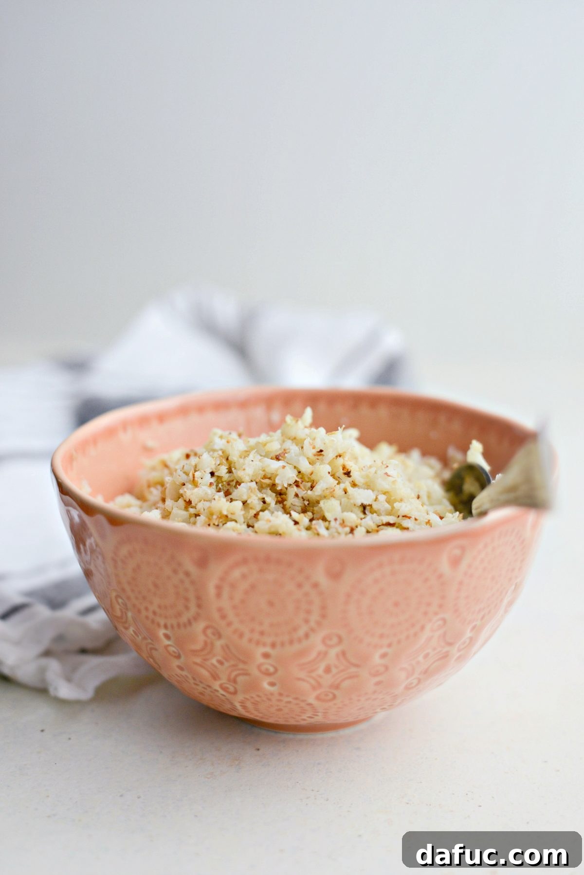 Crisp Roasted Cauliflower Grains 11 Bowl of roasted cauliflower rice with a spoon