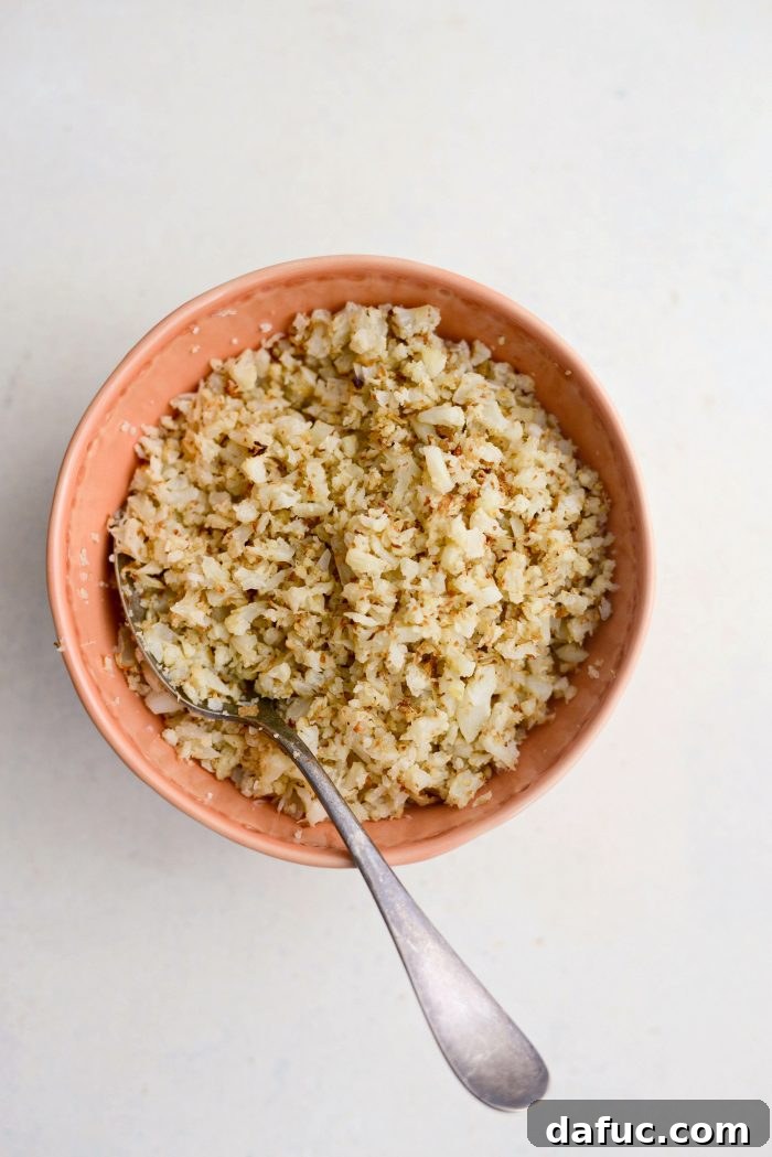 Crisp Roasted Cauliflower Grains 12 Roasted cauliflower rice in an orange bowl with a spoon