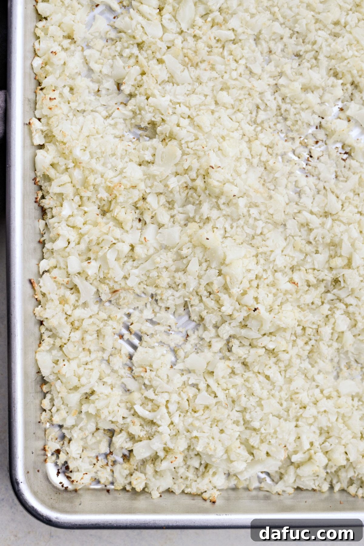 Crisp Roasted Cauliflower Grains 8 Roasted cauliflower rice being tossed in the pan
