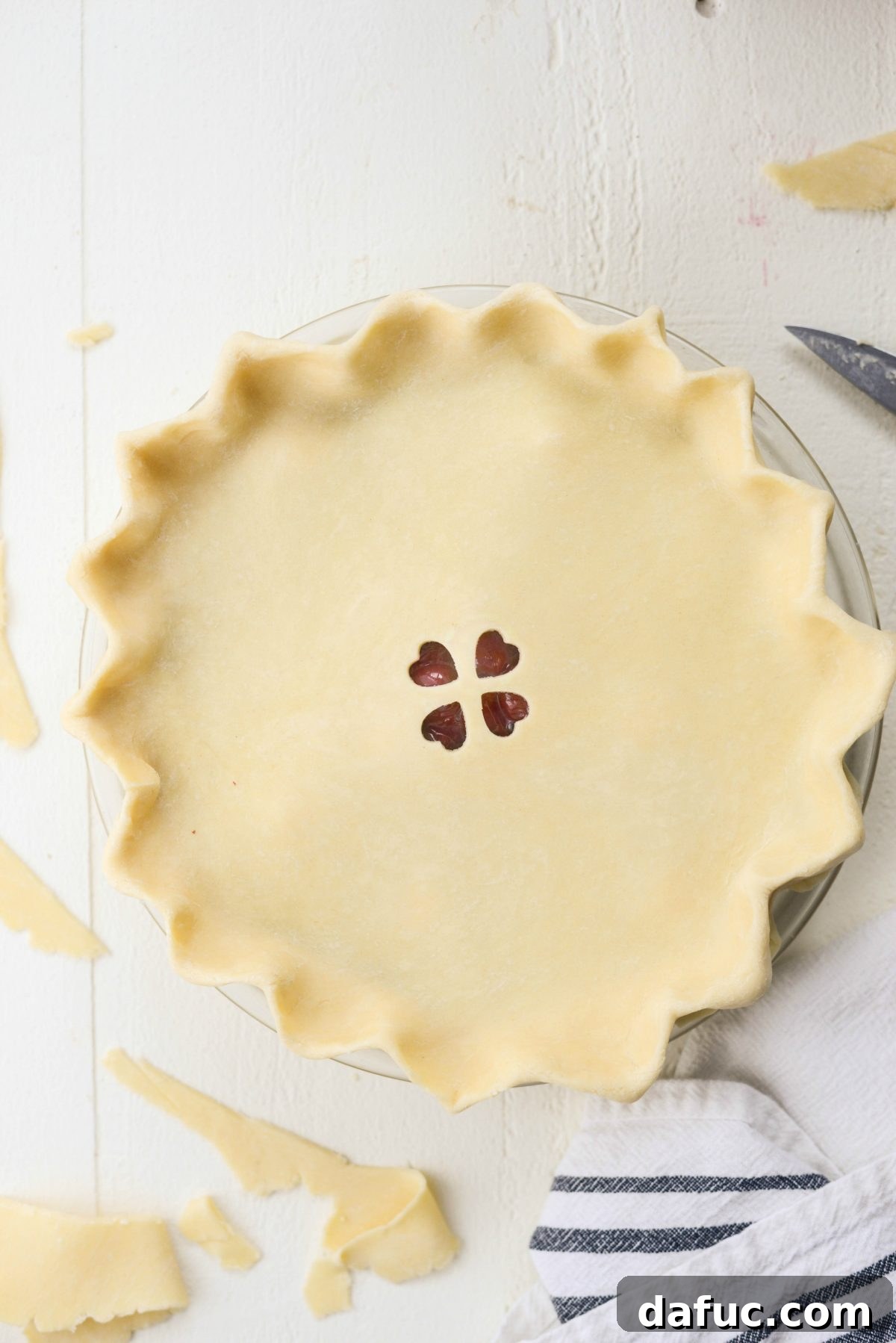 Adding top pie crust, pinching edges, and making cutouts for venting