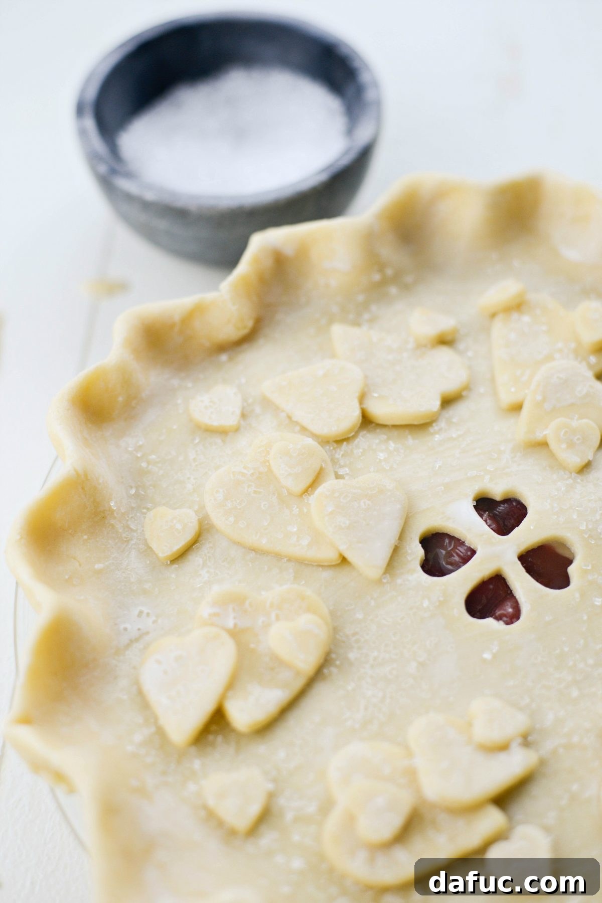 Brushing cherry pie with heavy cream and sprinkling with coarse sugar