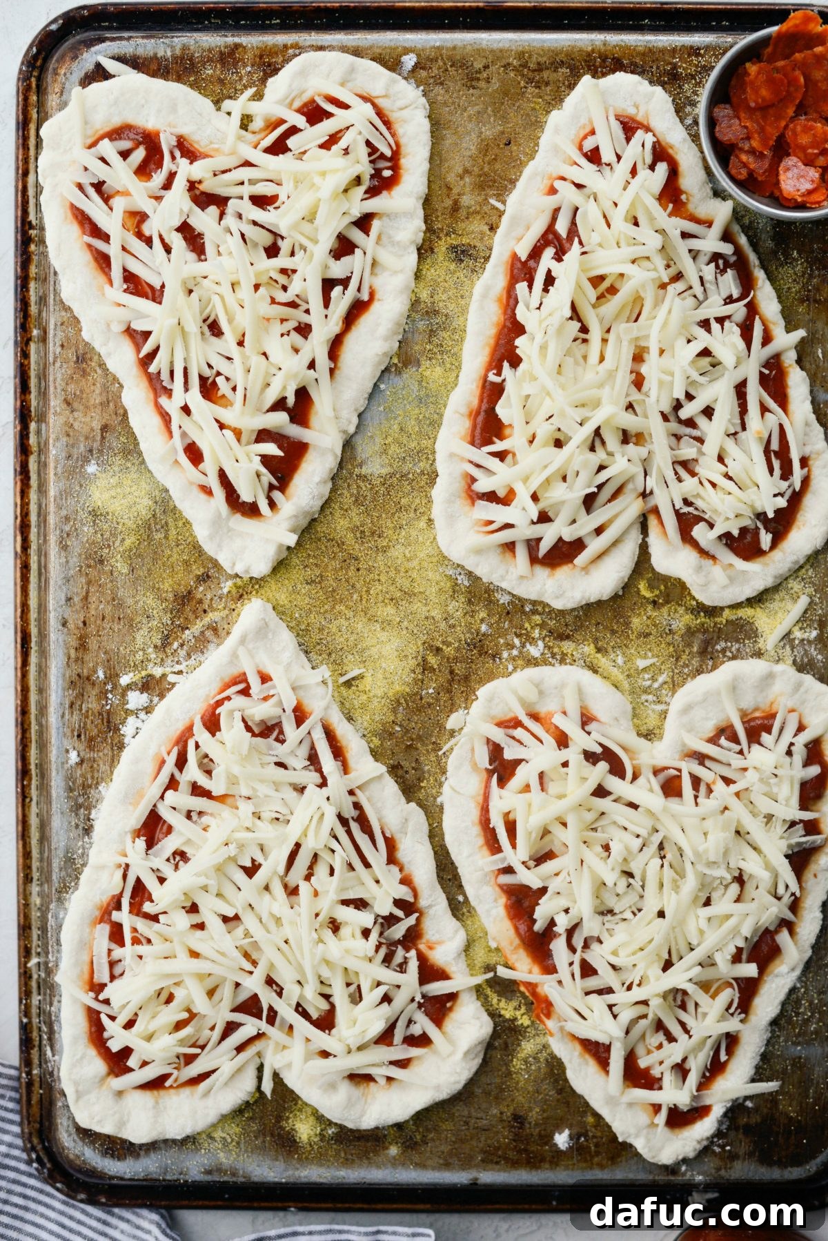 Sweetheart Pizza Treats 12 Sprinkling shredded mozzarella cheese on a heart shaped pizza