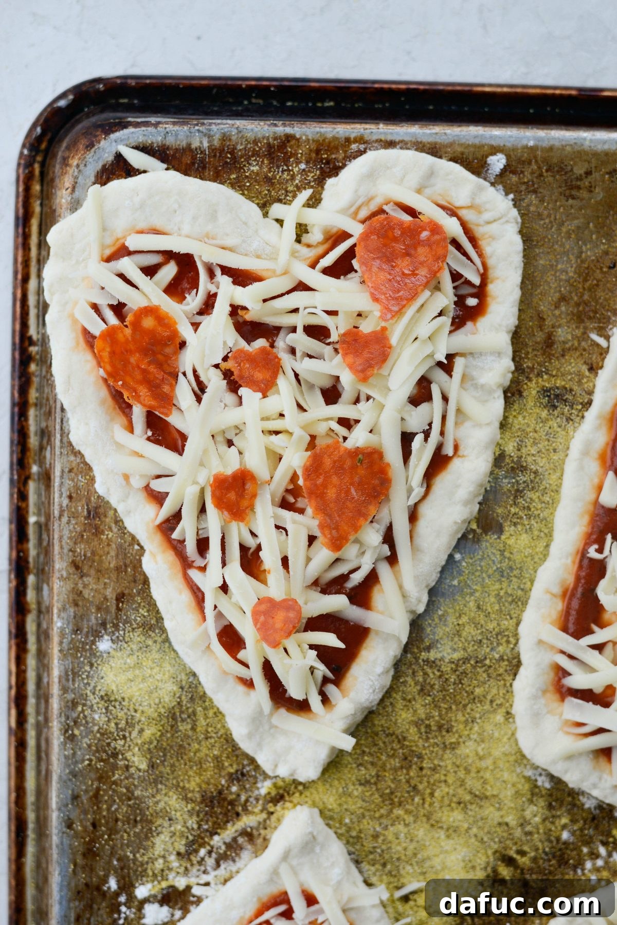 Sweetheart Pizza Treats 13 Topping heart shaped pizzas with pepperoni slices before baking