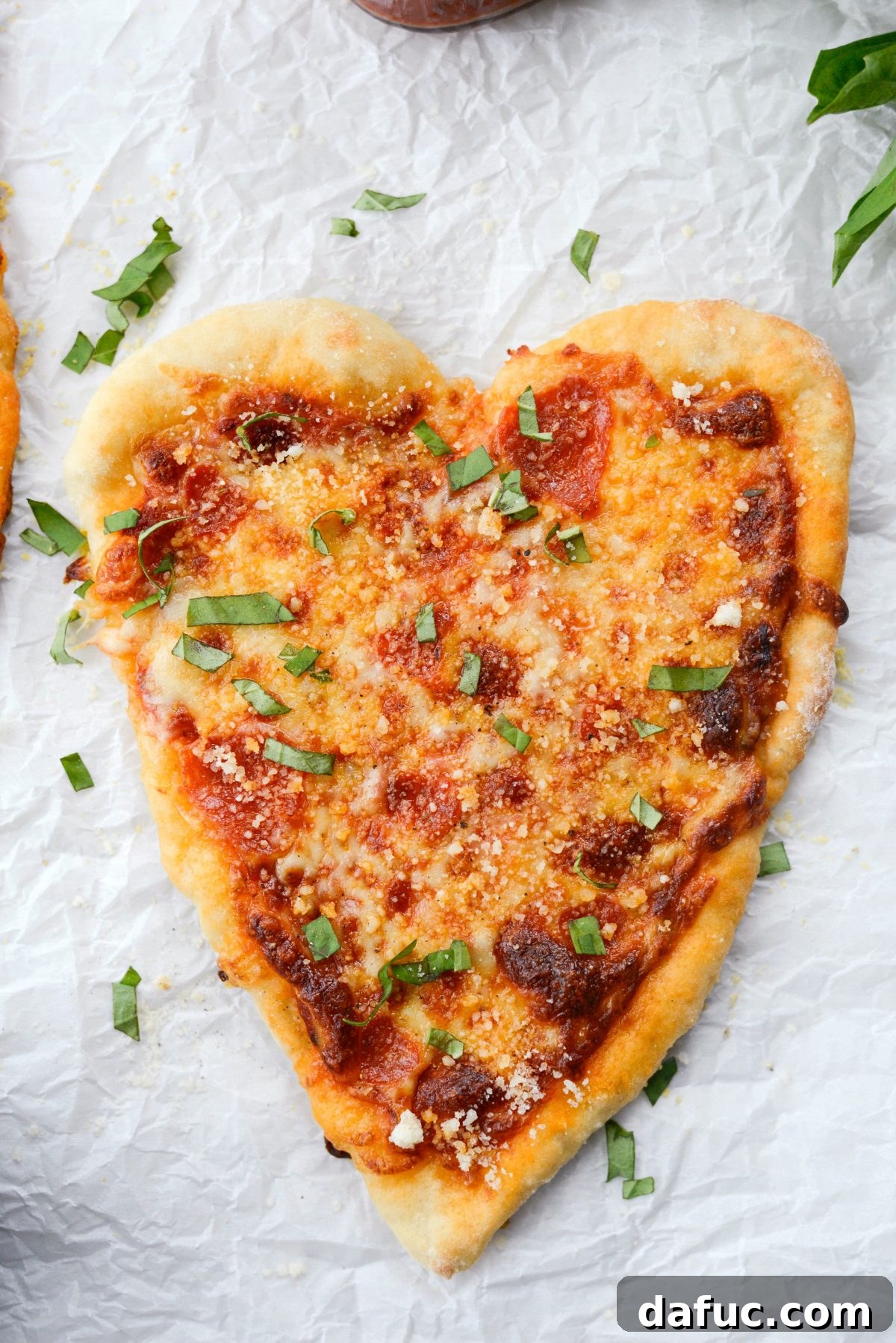 Sweetheart Pizza Treats 16 Close up of a Heart Shaped Personal Pizza garnished with fresh basil and Parmesan