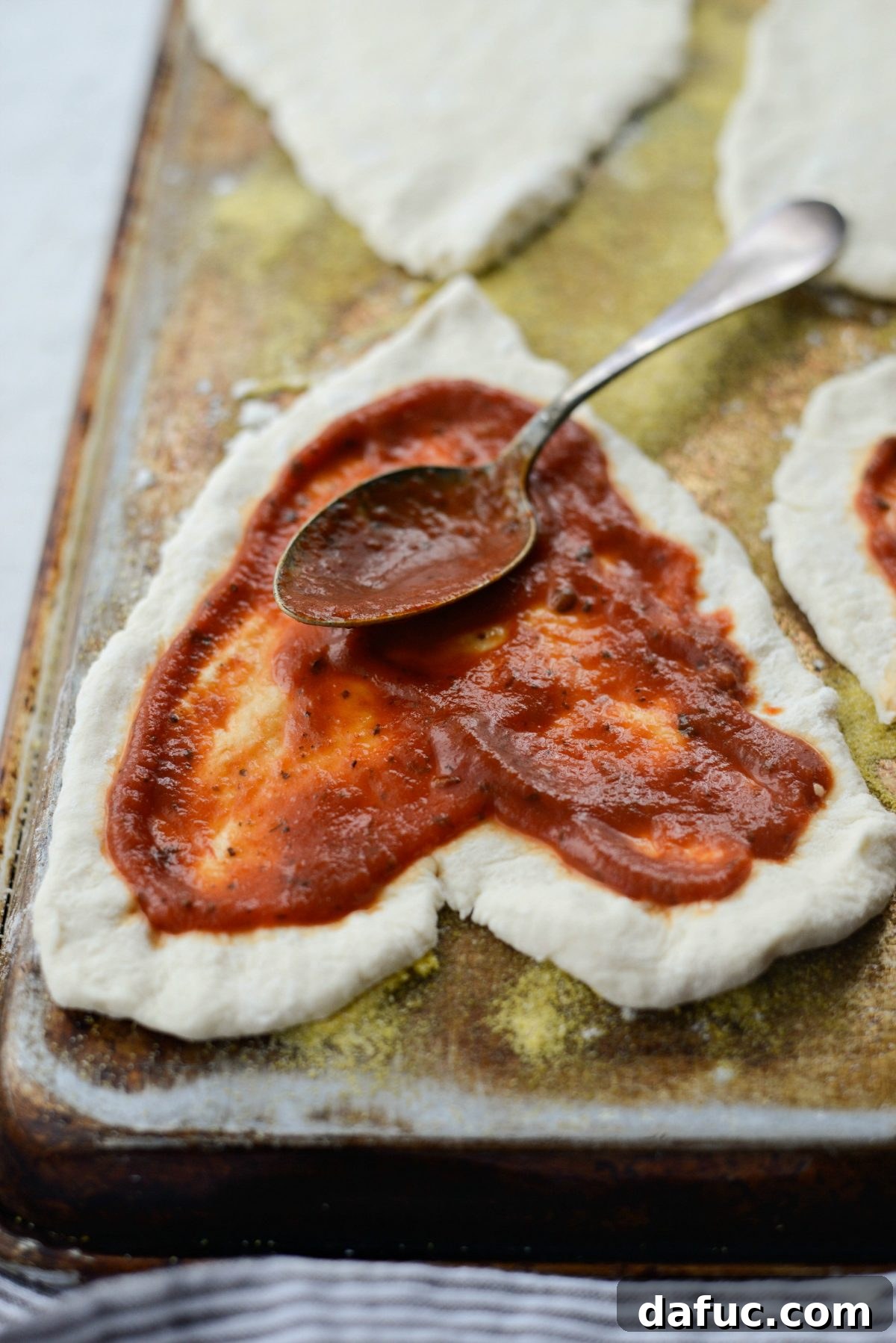 Sweetheart Pizza Treats 10 Spreading pizza sauce evenly on a heart shaped pizza dough