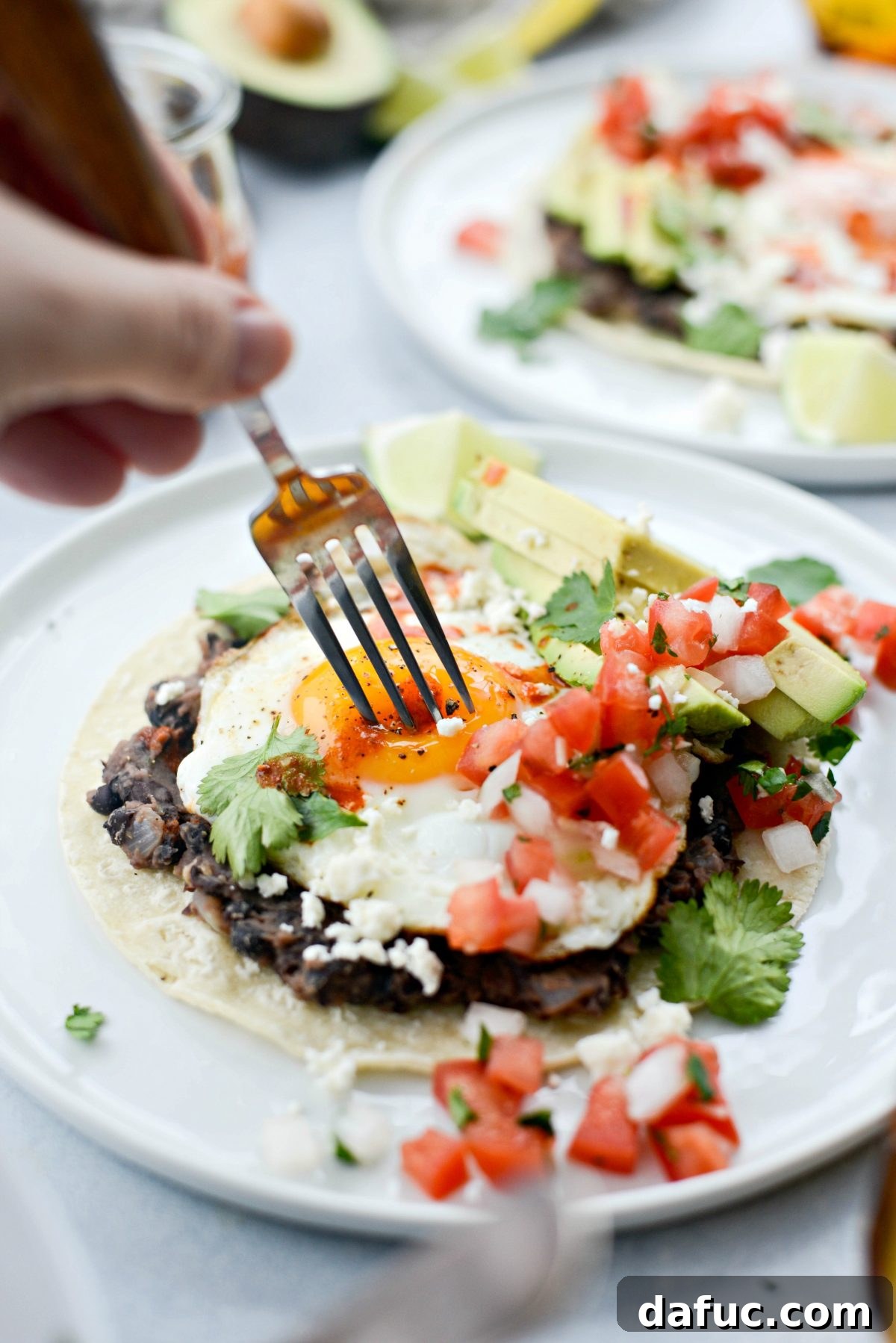 A fork piercing into a perfectly cooked Huevos Rancheros