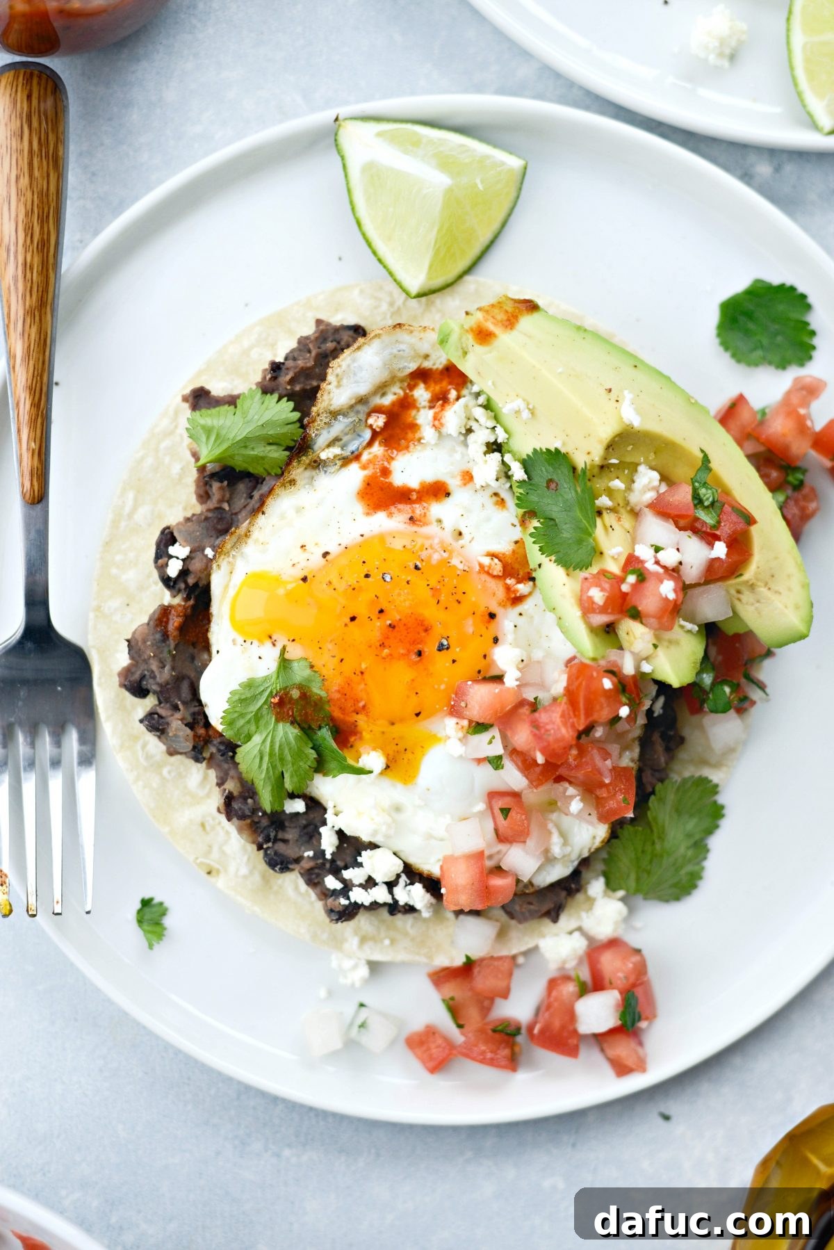 A detailed close-up of Huevos Rancheros with a fork ready to take a bite, highlighting the textures and layers