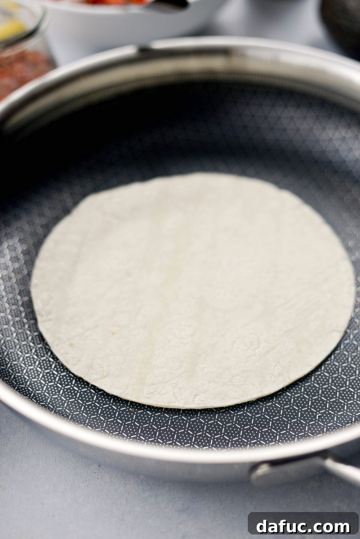 Corn tortillas being warmed in a nonstick skillet