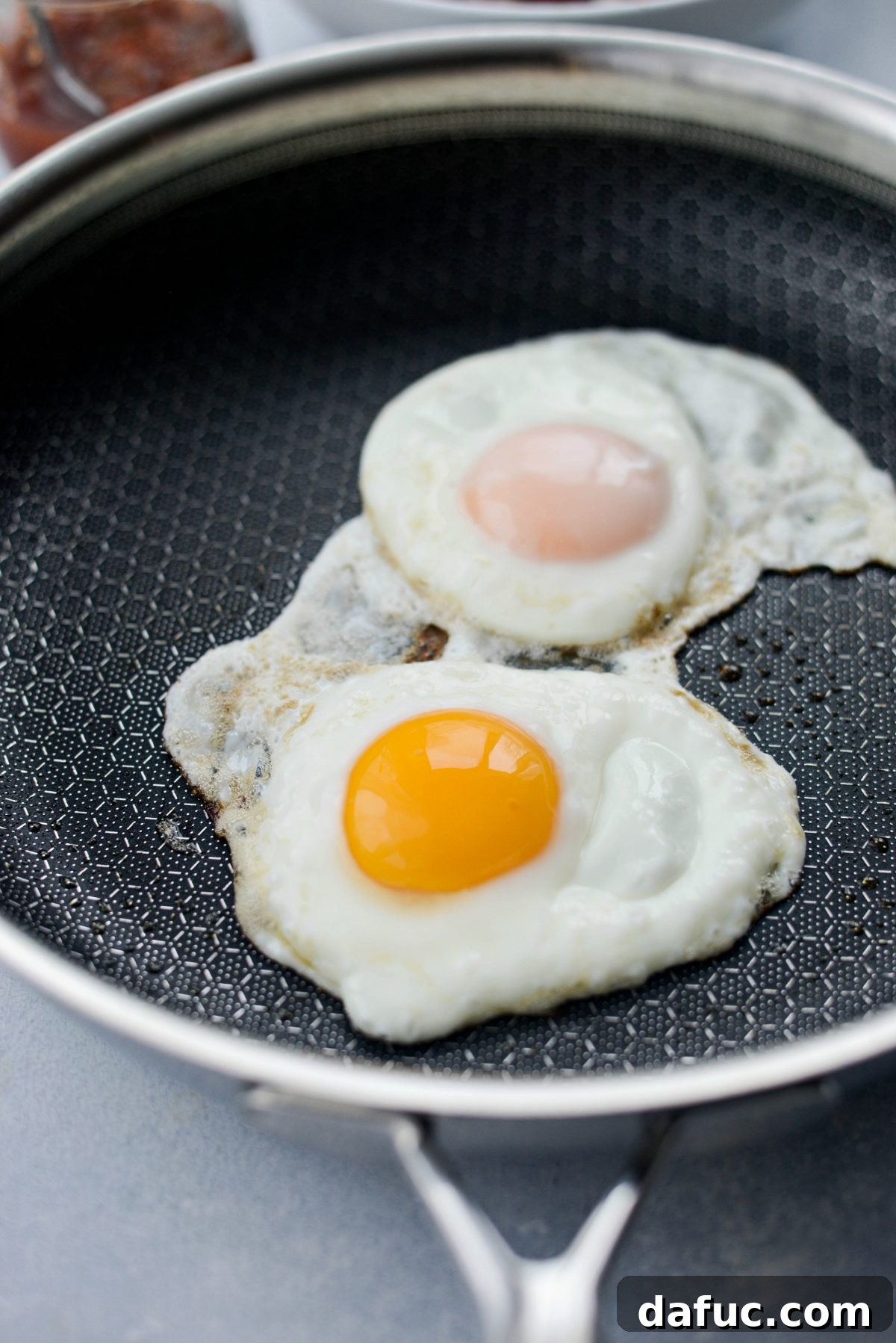 Eggs frying in a pan, ready for Huevos Rancheros