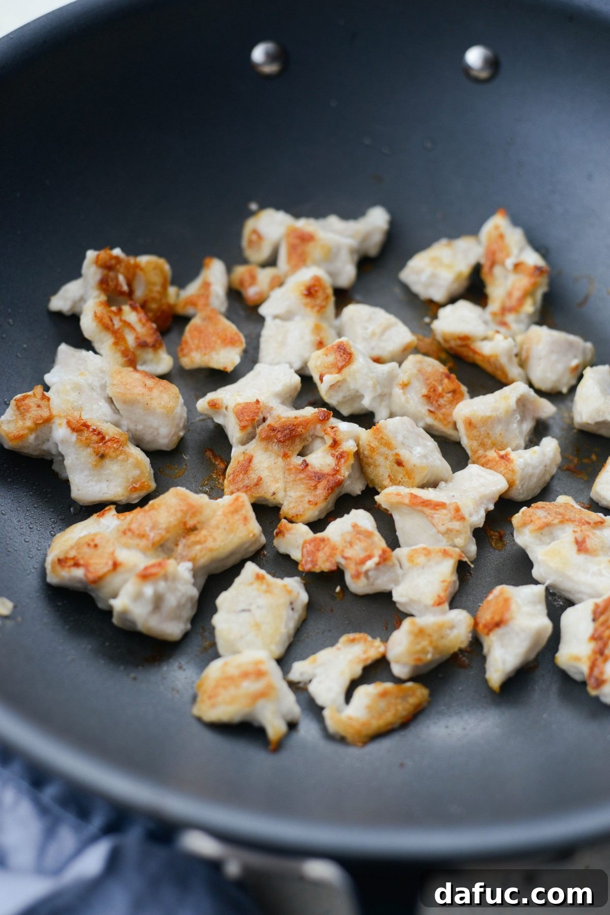 Crispy browned pieces of chicken cooked in a wok, showcasing the perfect sear.