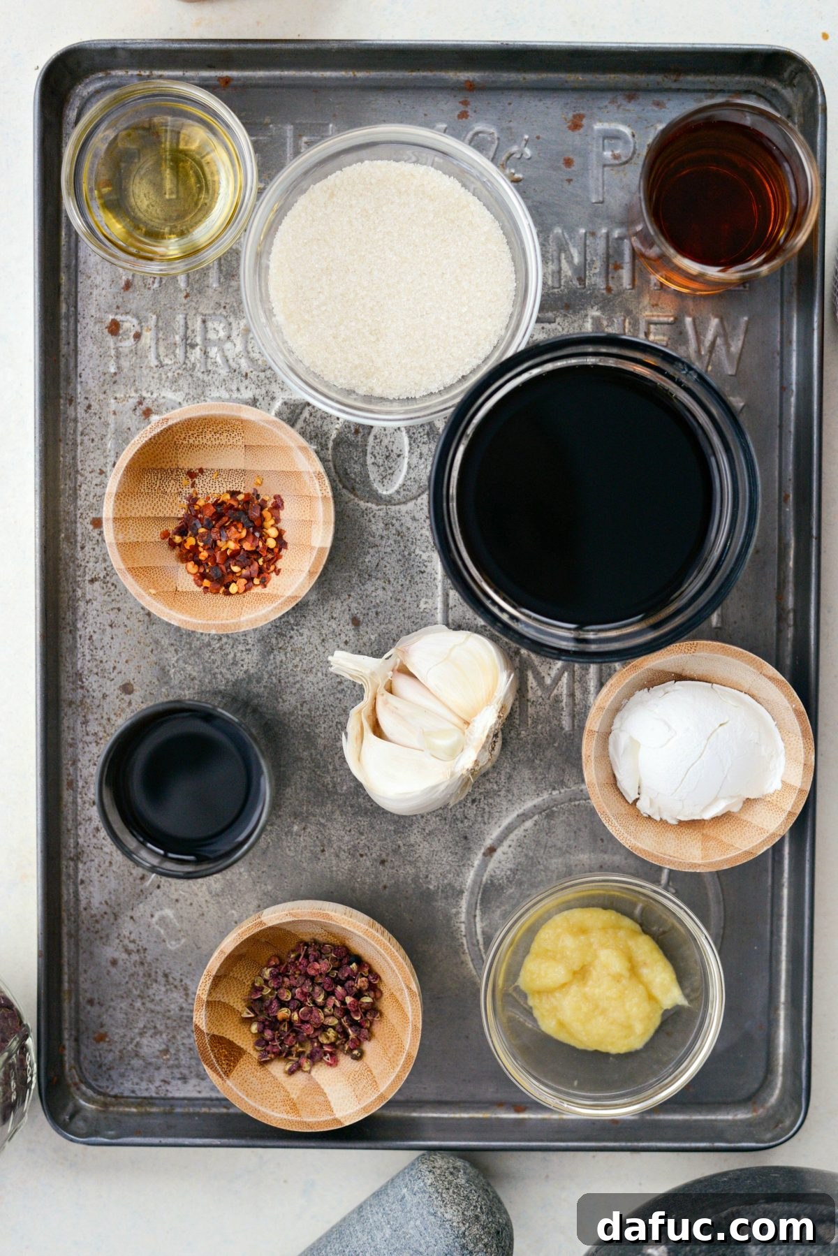 A collection of ingredients specifically for the homemade Kung Pao sauce, neatly arranged on a metal tray, showcasing various liquids and spices.