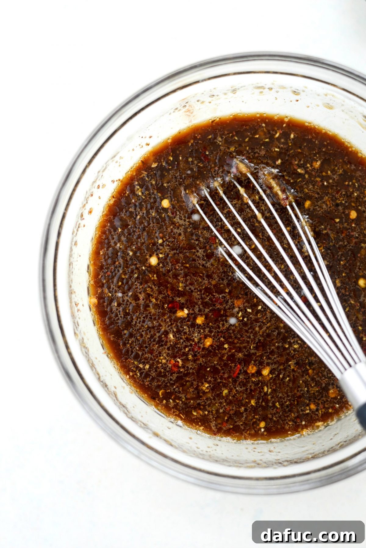 Close-up of the perfectly mixed homemade Kung Pao sauce in a bowl with a whisk, showing its smooth consistency.