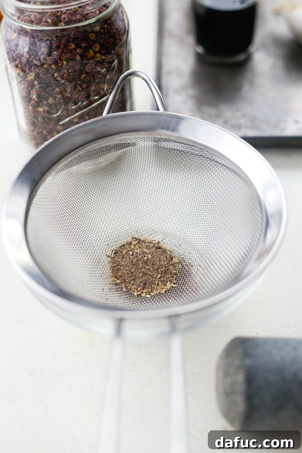 Szechuan Peppercorn Preparation Guide 7 Sifting ground Szechuan Peppercorns in a mesh sieve