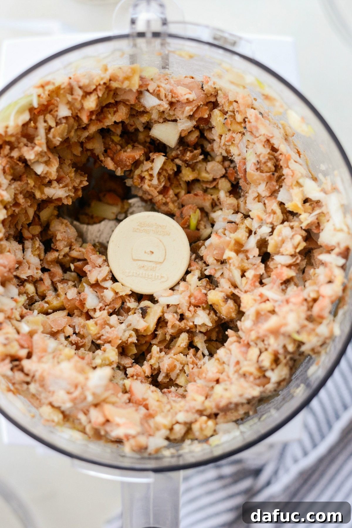 Food processor pulsing fava beans and walnuts into crumbles