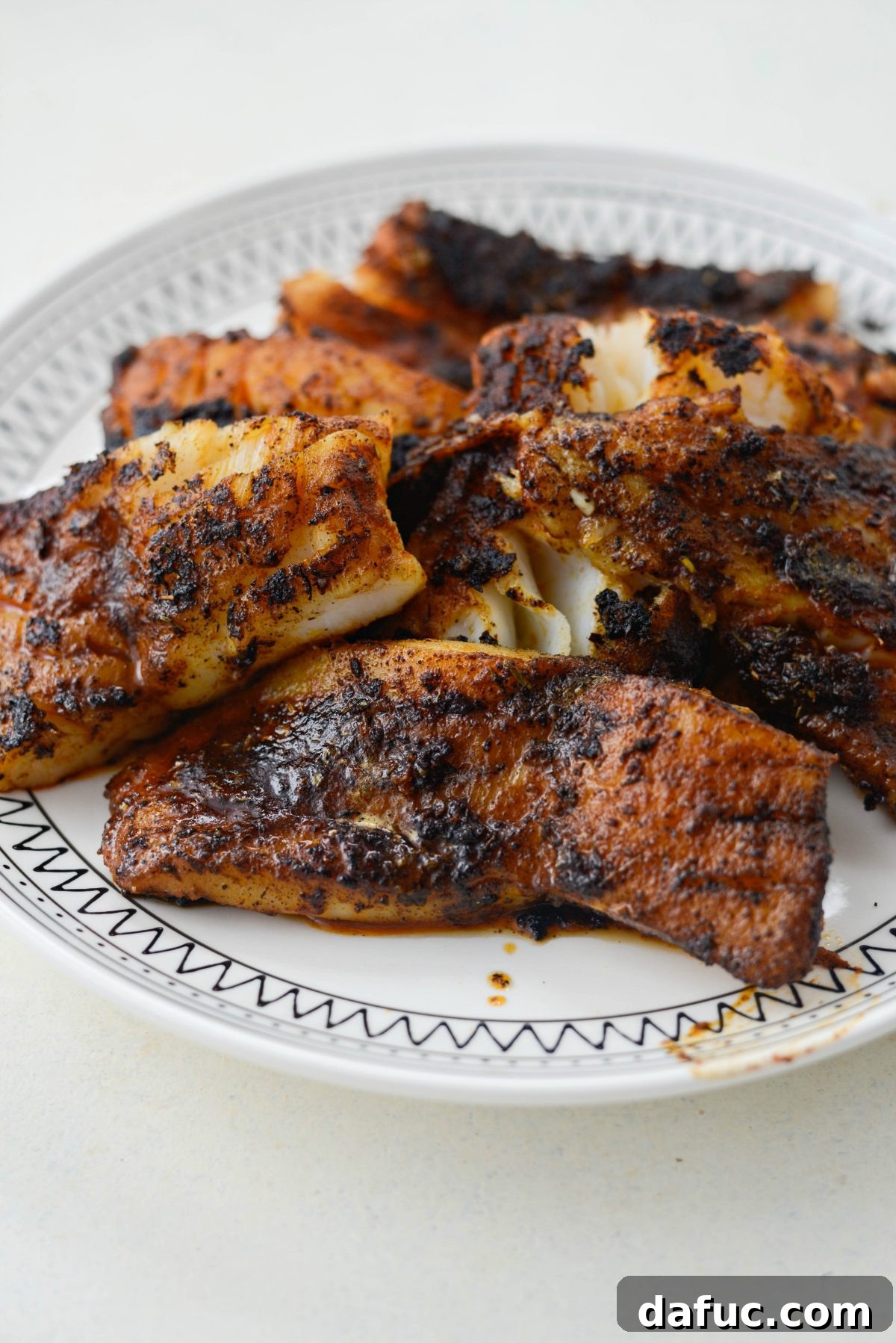 Plate of cooked blackened fish fillets