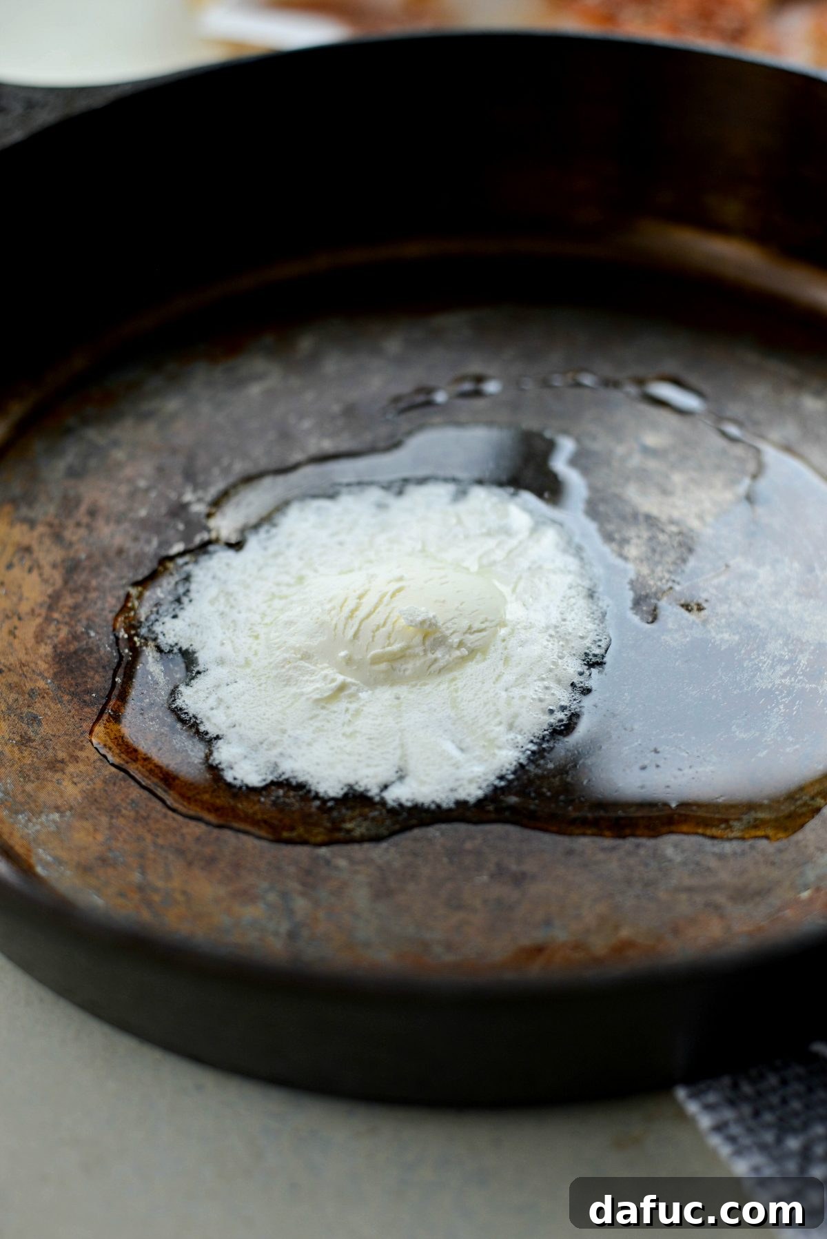 Melted butter and olive oil shimmering in a hot cast iron skillet.