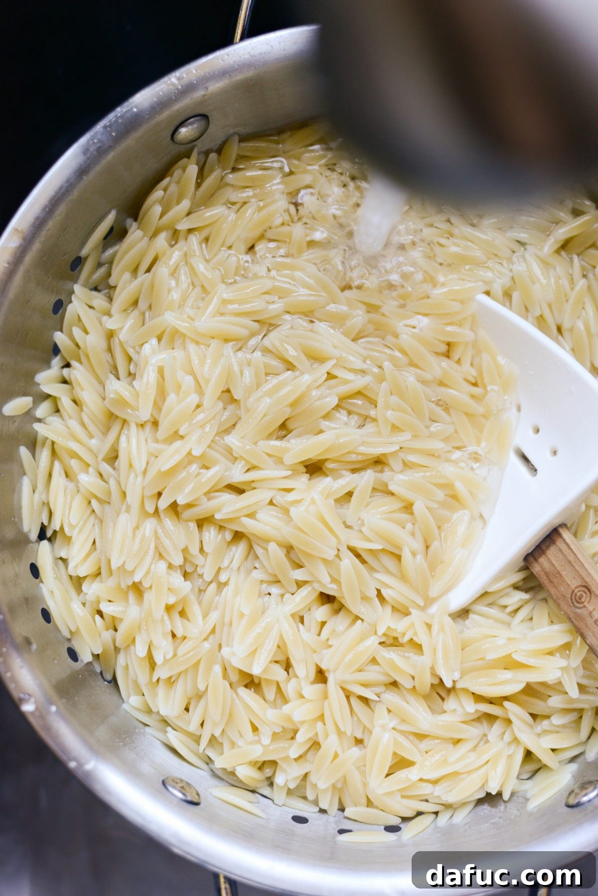 Vibrant Mediterranean Orzo Salad 6 Cooked orzo pasta being rinsed under cold water in a colander
