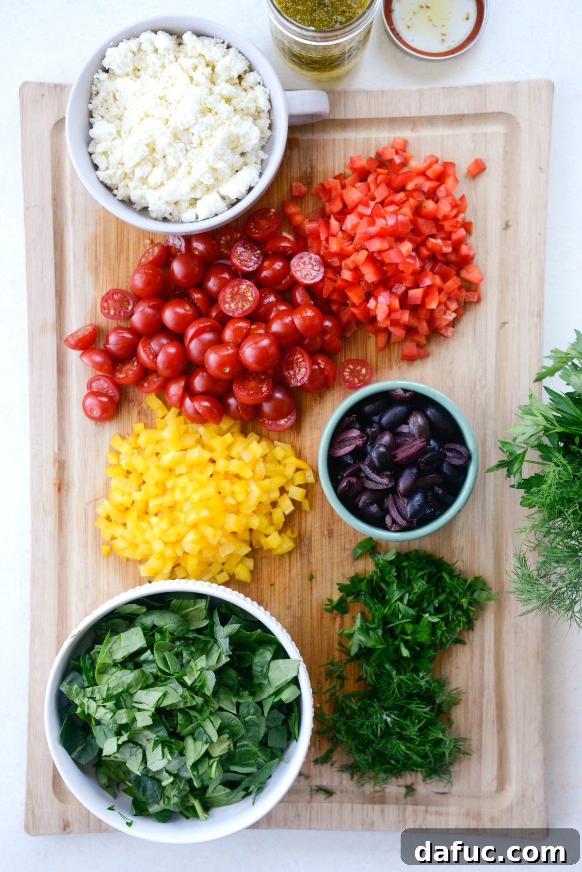 Vibrant Mediterranean Orzo Salad 7 Prepped salad ingredients laid out on a wooden cutting board