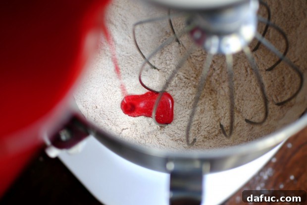 Timeless Red Velvet Cake 14 Pouring the vibrant red wet ingredients into the bowl of dry ingredients, initiating the creation of the Red Velvet Cake batter.