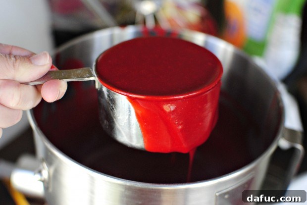 Timeless Red Velvet Cake 18 Using a measuring cup to evenly divide the rich red Red Velvet Cake batter between two prepared cake pans.