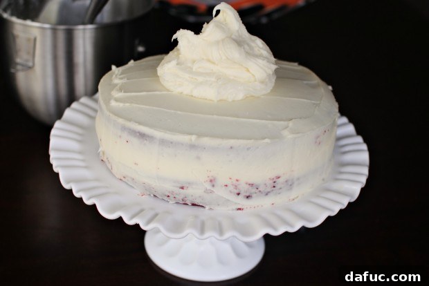 Timeless Red Velvet Cake 28 Applying the remaining cream cheese frosting over the chilled crumb coat of the Red Velvet Cake for a smooth, final finish.