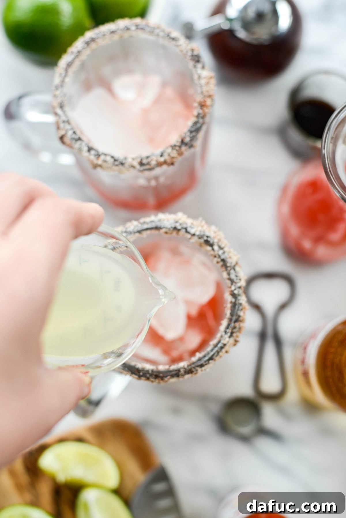 Pouring Clamato juice into the prepared Michelada mugs