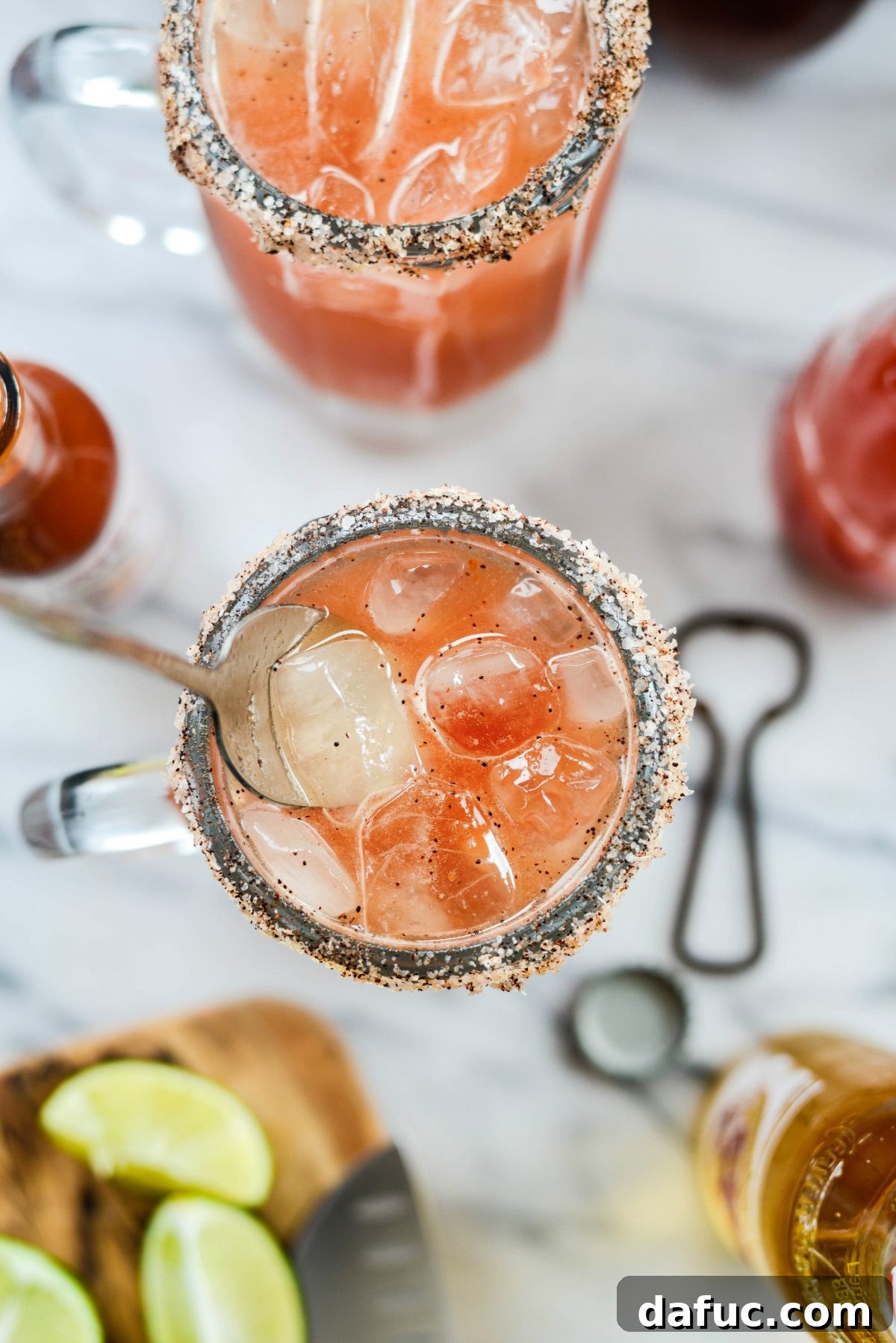 A Michelada cocktail being gently stirred with a spoon to blend flavors