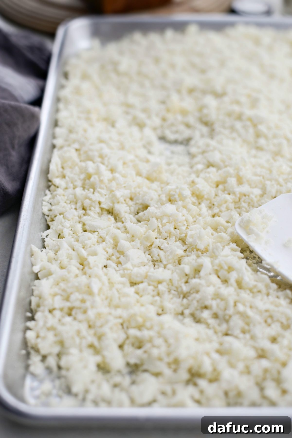 Close-up of raw cauliflower rice ready for roasting on a baking sheet