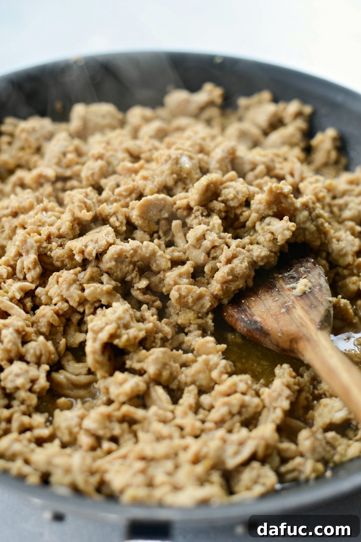 Ground chicken simmering in a rich, bubbling Thai sauce in a skillet