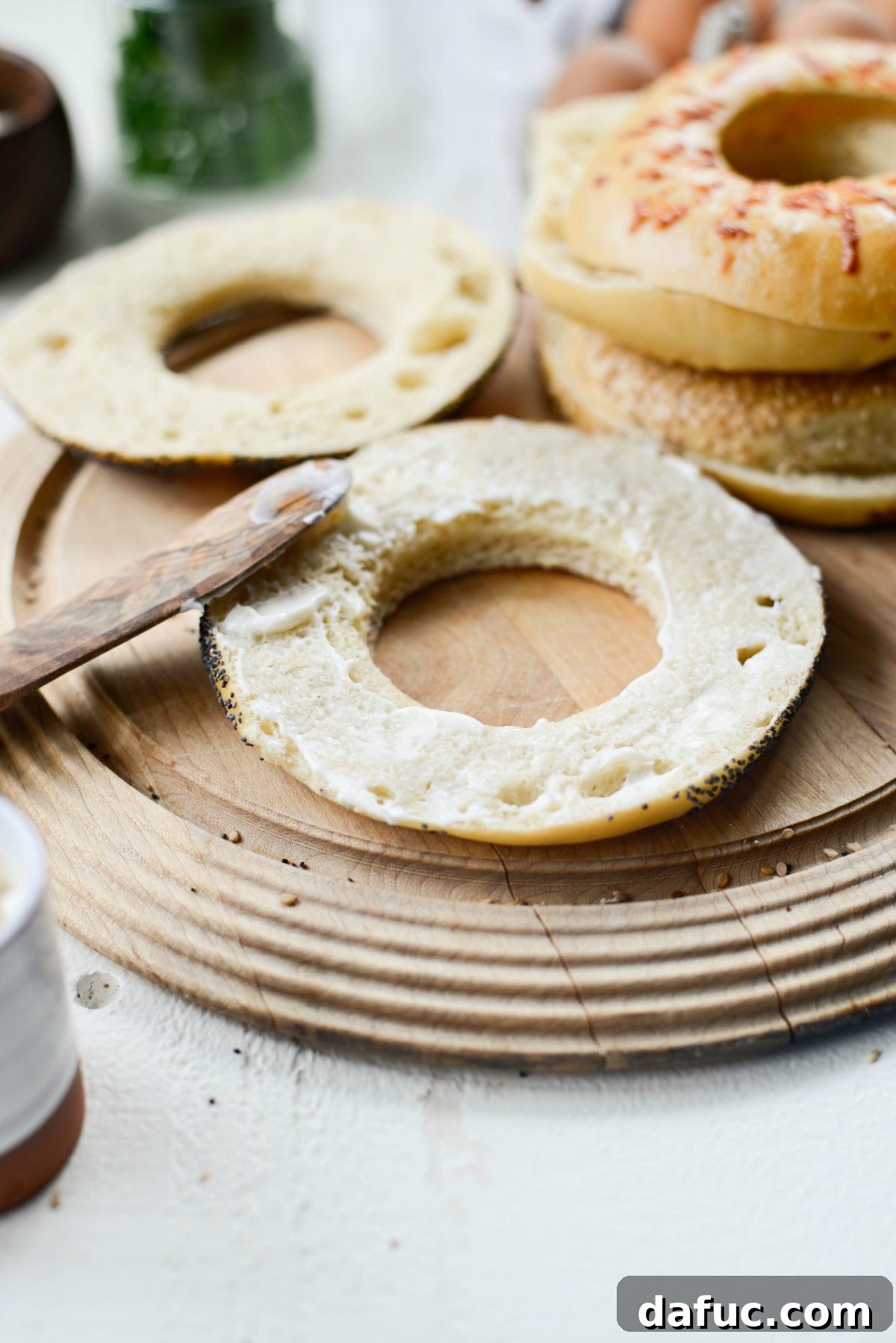 Bagel Egg Nests 9 A hand spreading mayonnaise on the cut side of a bagel half