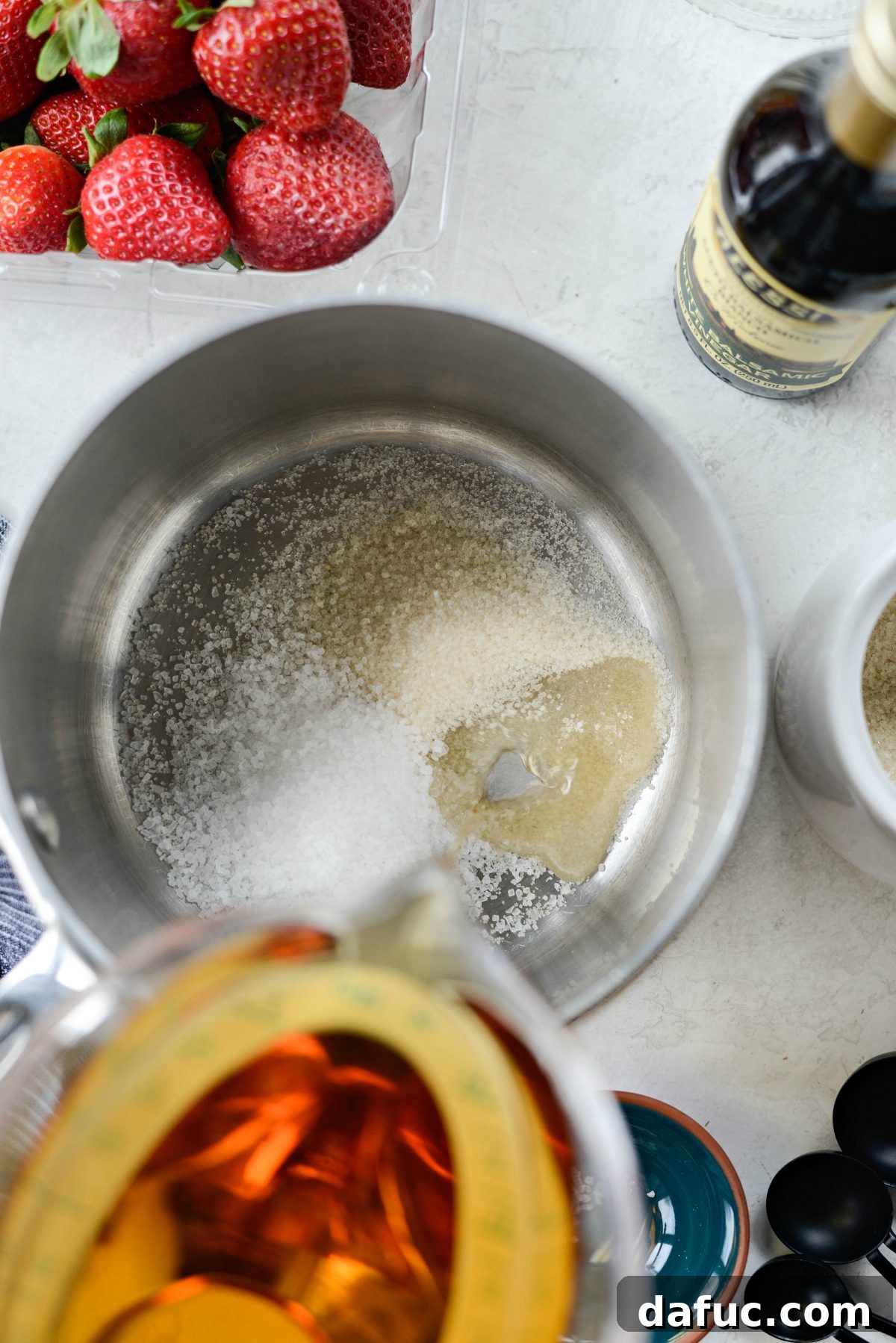 Vinegar-Kissed Strawberries 5 White balsamic vinegar being added to a saucepan with sugar, salt, and water.