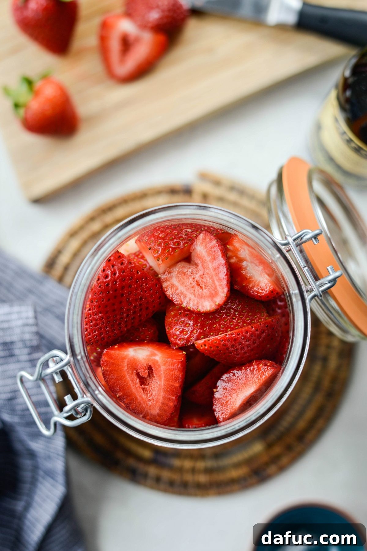 Vinegar-Kissed Strawberries 9 Halved strawberries being added to a glass jar in preparation for pickling.