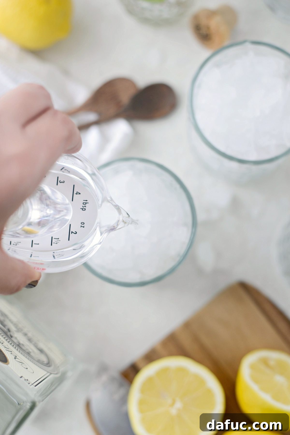 Gin being poured into an ice-filled glass for a Lemon Gin Fizz