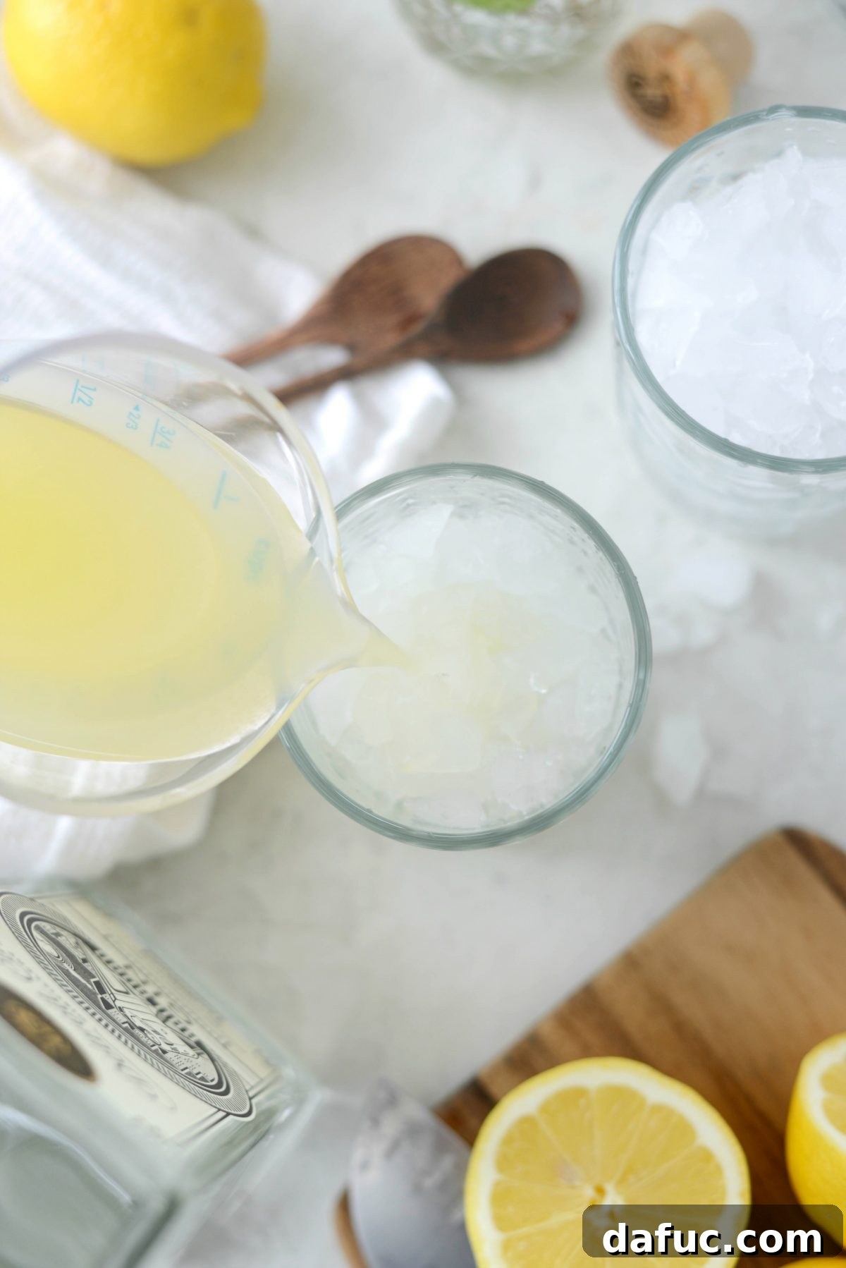 Fresh lemon juice being squeezed into a cocktail glass for a Gin Fizz