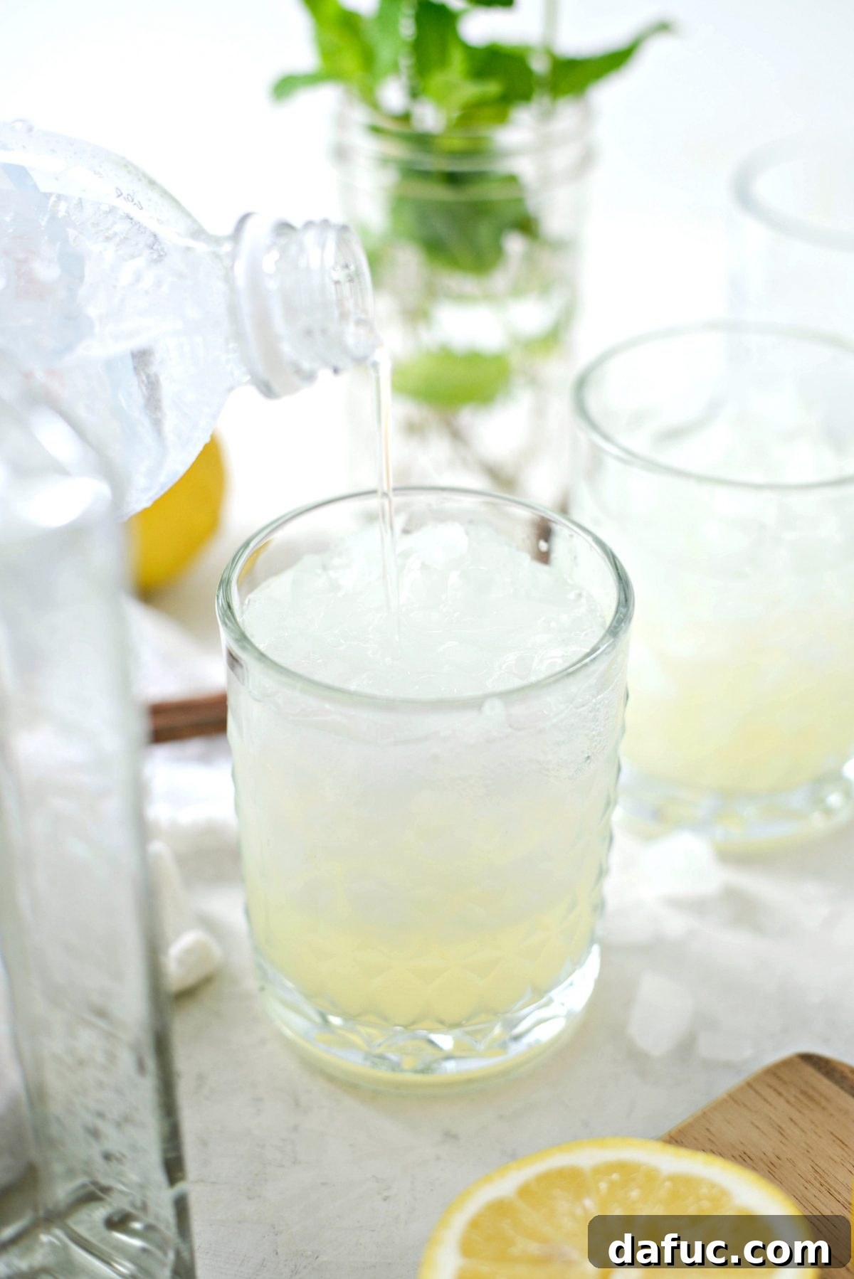 Club soda being poured over the gin and lemon mixture to create the fizz effect
