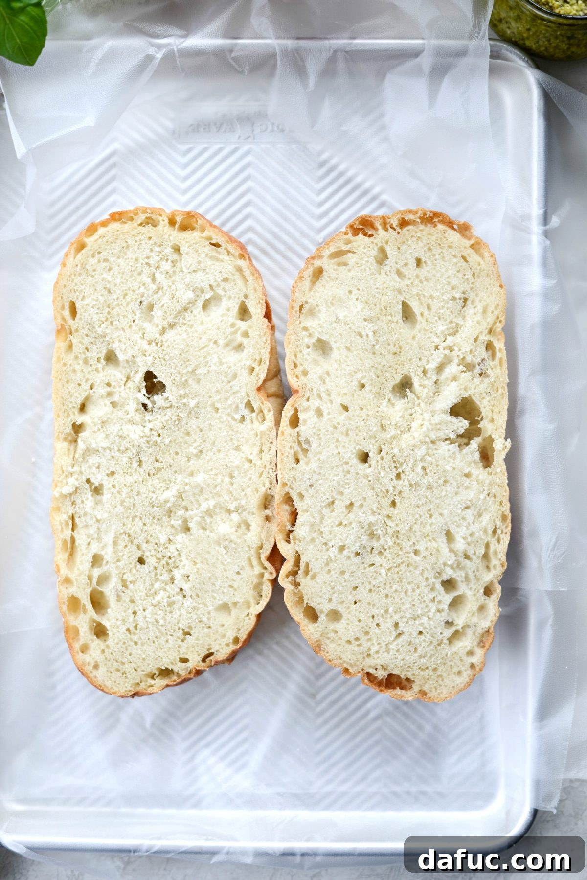 Pressed Italian Perfection 5 Bread halves on plastic wrap set into a rimmed tray, ready for assembly.