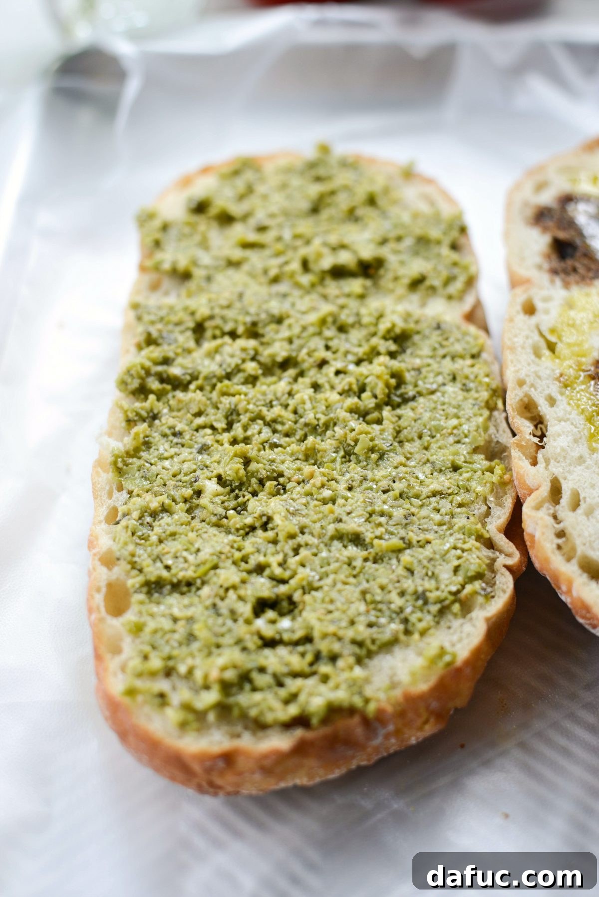 Pressed Italian Perfection 7 Olive tapenade or basil pesto spread on the bottom half of the bread.