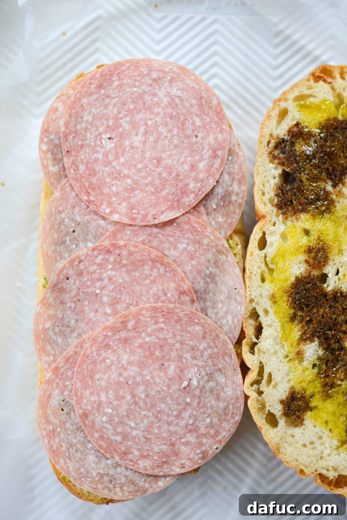 Pressed Italian Perfection 8 Layer sliced salami on the bottom bread half.