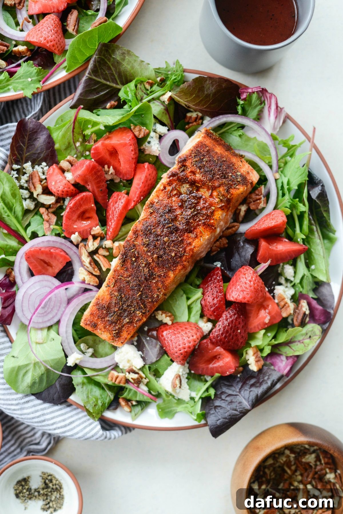 A single portion of Blackened Salmon Salad with Strawberry Peppercorn Vinaigrette, ready to be served.