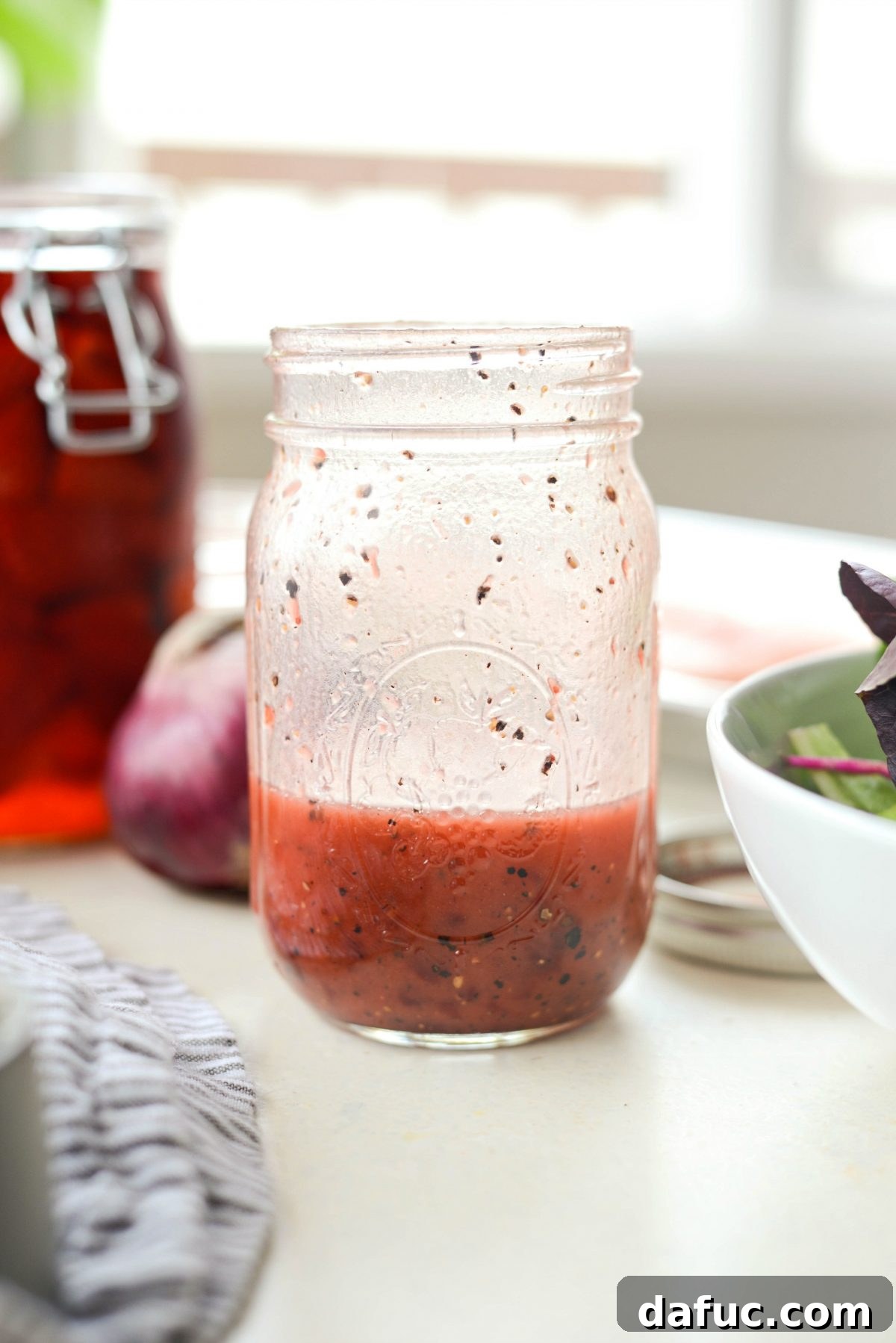 Smooth, vibrant Strawberry Peppercorn Vinaigrette in a glass jar, ready to be drizzled over salad.