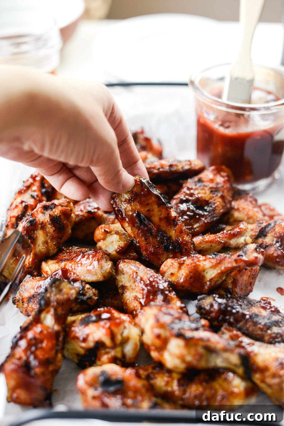 Sweet & Smoky Cherry Chipotle Wings 20 Someone picking up a Grilled Cherry Chipotle Chicken Wing, ready to enjoy