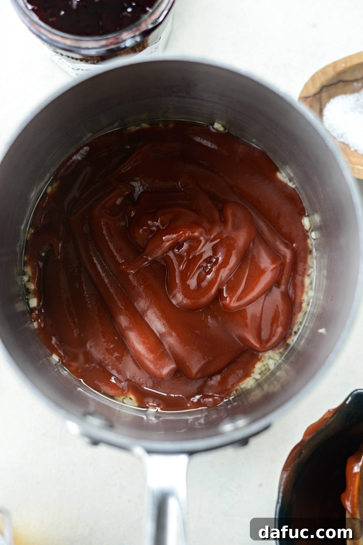 Adding ketchup to the sautéed garlic base for the BBQ sauce
