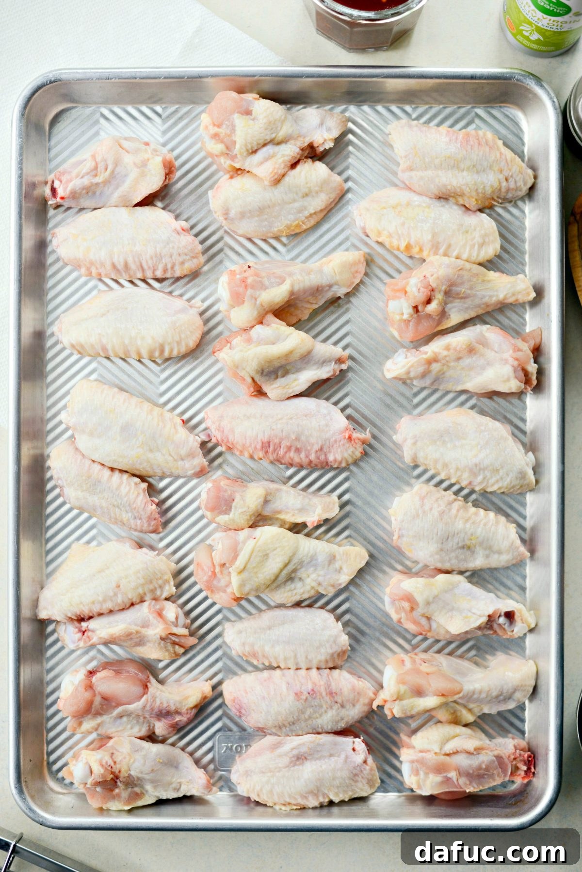 Sweet & Smoky Cherry Chipotle Wings 10 Raw chicken wings arranged on a rimmed sheet pan, prepped for grilling
