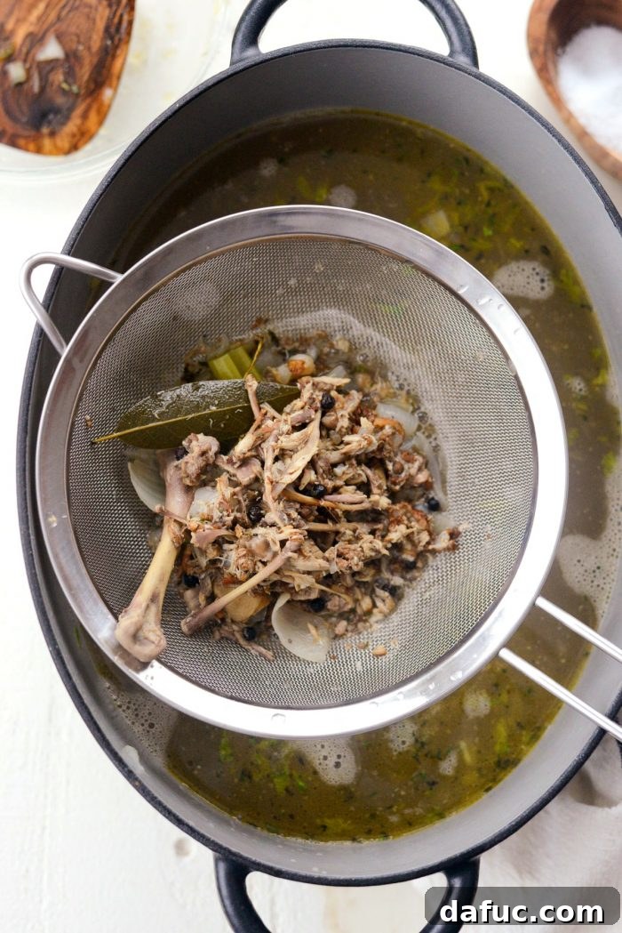 Removing large vegetables and bones from the finished chicken stock