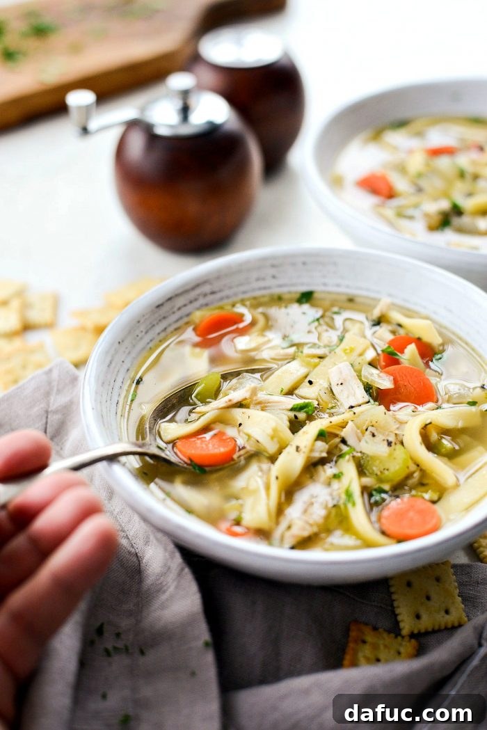 A steamy bowl of homemade chicken noodle soup, garnished with fresh herbs