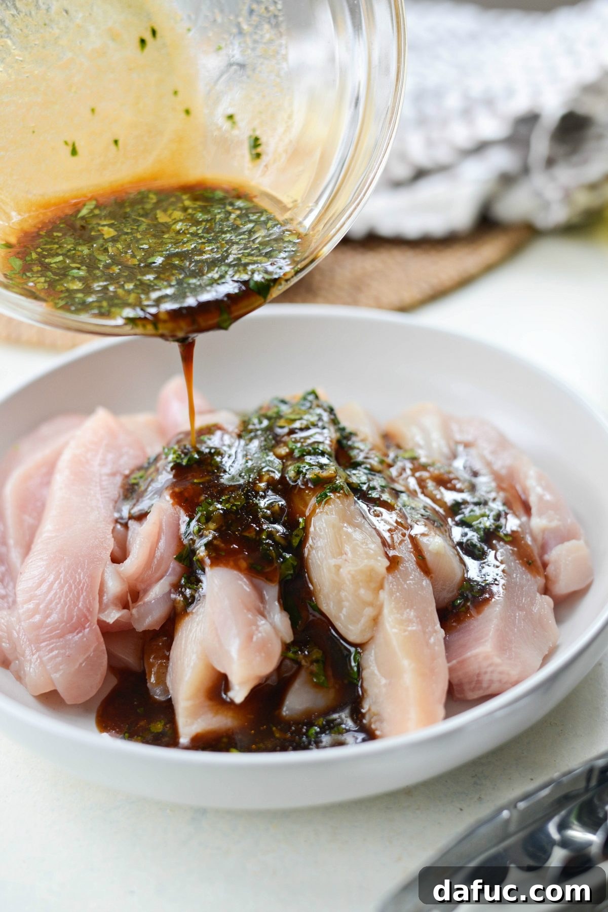 Thai Chicken Satay Skewers with Creamy Peanut Sauce 10 Pouring marinade over strips of chicken in a bowl