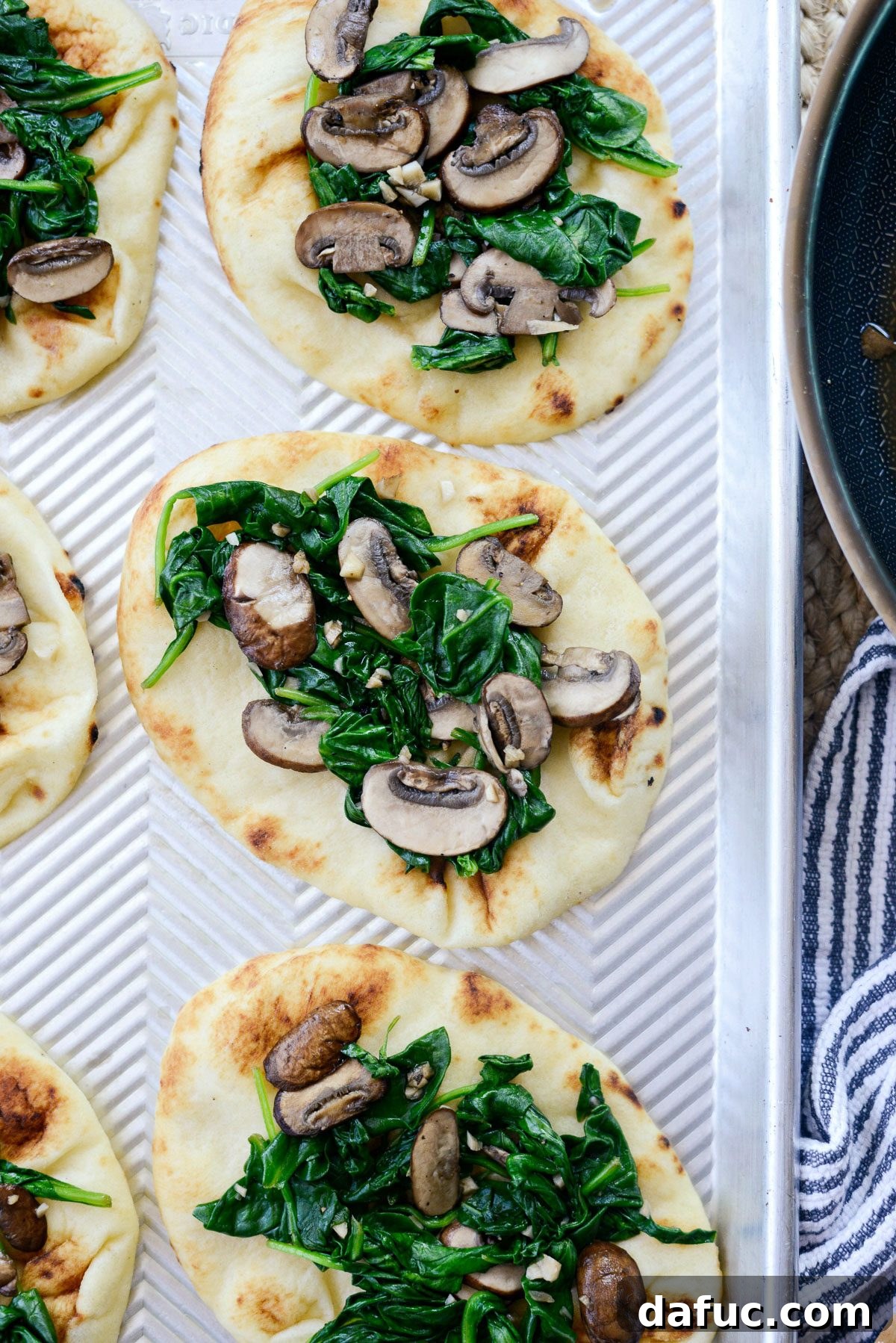 Baby spinach wilting in a skillet with mushrooms.