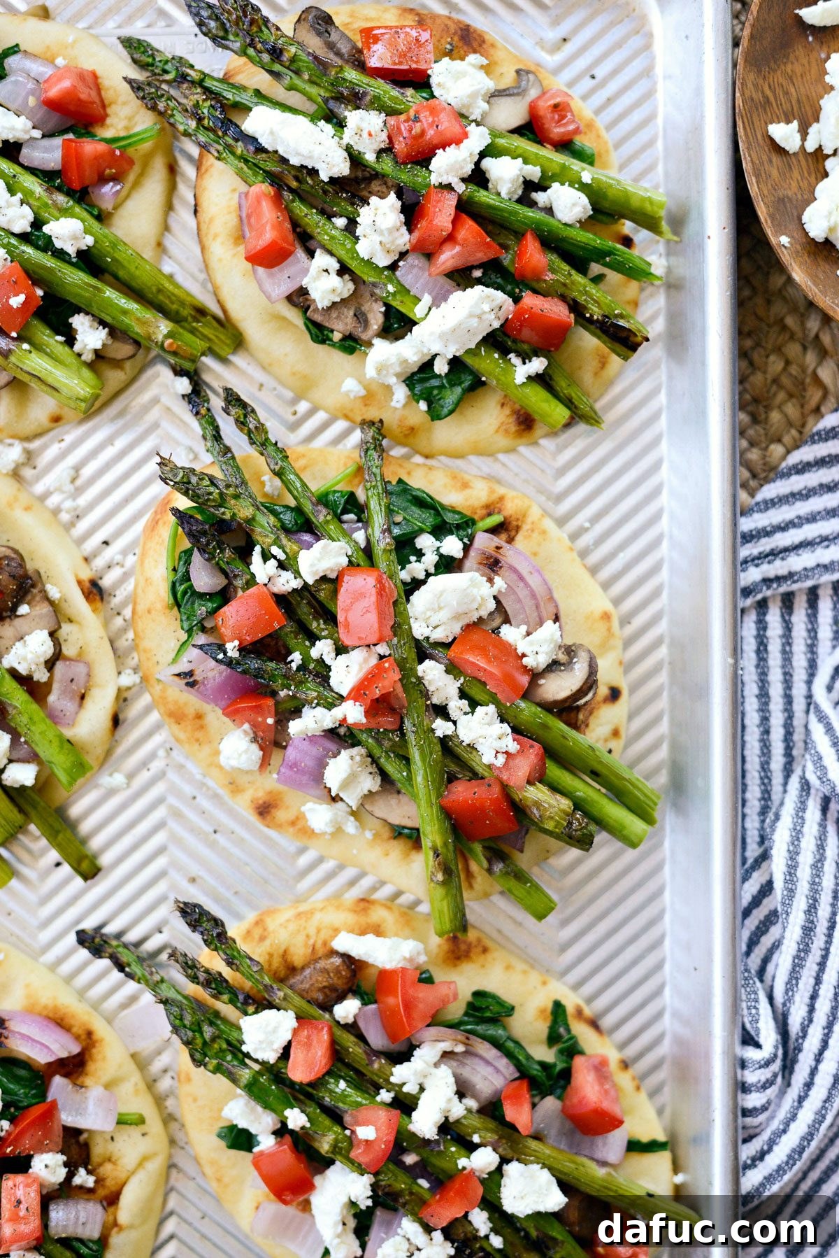 Naan breads arranged on a baking sheet, ready for toppings.