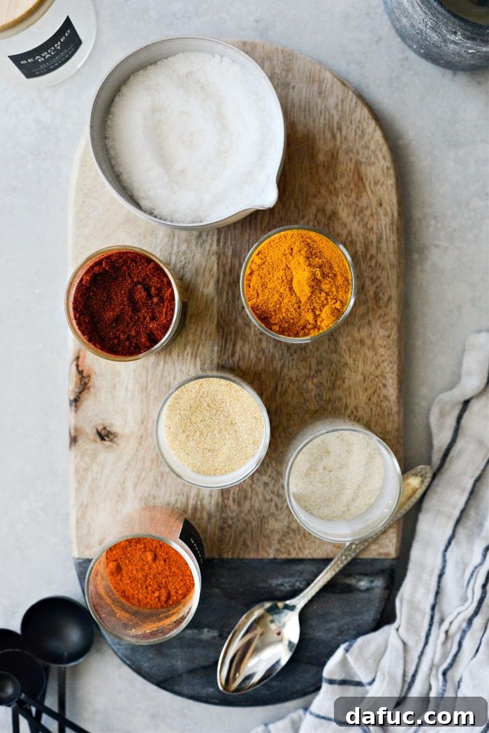Individual spices laid out on a table, including fine sea salt, paprika, turmeric, garlic powder, onion powder, and cayenne pepper